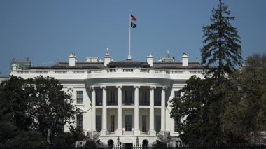 Beyaz Saray, simgesel mimarisini ve bayrağını gösteren açık mavi gökyüzüne karşı Washington DC 'de canlı bir bahar gününün sinyallerini veriyor..