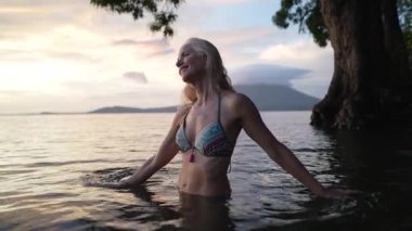 Mutlu, olgun bir kadın Nikaragua 'daki Concepcion Gölü' nün suyunda duruyor. Arkaplanda bir volkanla güzel manzaranın ve sükunetin tadını çıkarıyor..