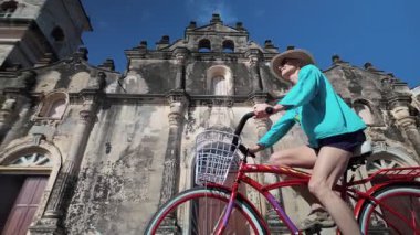 Olgun bir kadın, tarihi La Merced Kilisesi yakınlarındaki Granada, Nikaragua 'da bisiklet sürmekten hoşlanıyor. Bu güzel gün, Orta Amerika 'daki turizm deneyimini arttırıyor..