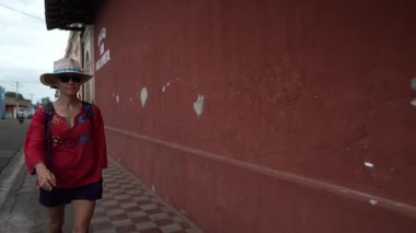Olgun bir kadın, Granada, Nikaragua 'da renkli bir duvarda yürüyor ve bu tarihi Orta Amerika şehrinde kültürel deneyimlerinin tadını çıkarıyor..