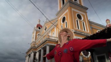 Nikaragua, Granada 'da canlı bir kilisenin önünde kollarını açmış, Orta Amerika' nın güzelliğini kucaklayan olgun bir kadın..
