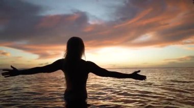 Mutlu, olgun bir kadın gün batımında dinlendirici sularda yürür. Tatilde okyanusun ya da gölün dinginliğini kucaklar..