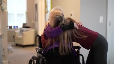 Aile bireyleri bir bakım merkezinde samimi bir kucaklaşmayı paylaşarak, bir ziyaret sırasında sevgi ve bağın altını çiziyor. O an neşeyi ve birlikteliği yakalar..