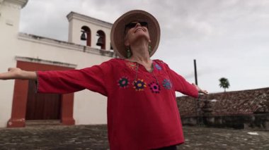 Granada manastırının önünde durmuş, tarihi manastırın güzelliğini kucaklayan ve Nikaragua 'daki seyahat deneyiminin tadını çıkaran olgun bir kadın..