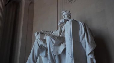 Washington 'daki Lincoln Anıtı' nın içindeki Abraham Lincoln mermer heykelinin yakın çekimi. Sağ kolu sandalyede dinlenirken, sol bacağı sağ bacağının üzerinde kesişti..