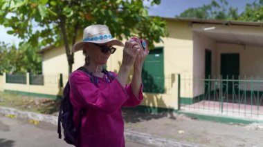 Olgun bir kadın Moyogalpa, Ometepe Adası 'nda, yemyeşil bir alanda telefonuyla fotoğraf çekerken gülümsüyor. Güneşli gün, onun neşeli Orta Amerika seyahat deneyimini vurguluyor..