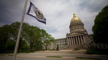 İkonik altın kubbesine sahip Batı Virginia Eyalet Meclisi Charleston 'da gururla duruyor. Ziyaretçiler bulutlu bir gökyüzünün altındaki araziyi keşfediyorlar.