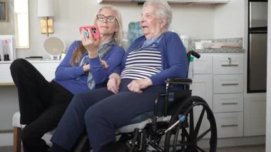 Bir kız ve yaşlı annesi evde sıcak bir video sohbetinin tadını çıkarıyorlar. Değerli anılarını yakalıyorlar ve sevgi ve destekle bağlarını güçlendiriyorlar..