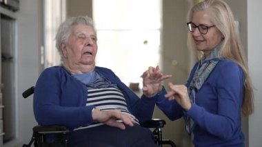 Sevgi dolu bir kız, yaşlı annesine tekerlekli sandalyede destek olur ve evinde rahat bir anı paylaşır. Aralarındaki bağ, günlük yaşamlarını ve bakımlarını ön plana çıkarıyor..