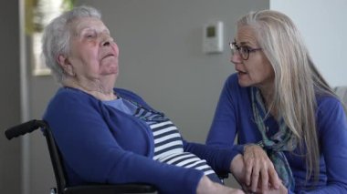 Yaşlı bir kadın ve kızı arasındaki sıcak etkileşim, kapalı bir ortamda. Birlikte geçirdikleri her gün boyunca sevgi ve ilgi gösterirler..