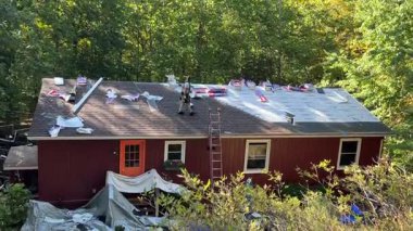 Berkeley Springs, WV, ABD - 09 27 2023: Eski çatı kiremitlerini söken işçilerin düşük hava manzarası, ev yenileme projesinde yeni bir çatı ile değiştirilecek