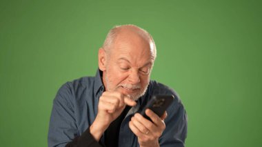 Olgun bir adam, duyurular ya da terfiler için katı yeşil bir ekranda izole edilmiş akıllı telefonunu kullanırken öfke ve hayal kırıklığını ifade eder..