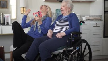 90 'lı yaşlarda bir kadın, kızıyla evde keyifli bir görüntülü sohbet etmekten hoşlanır. Kahkahaları paylaşıyorlar ve sıcak ve destekleyici bir ortamda sevgi dolu anılar yaratıyorlar..