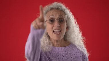 Beyaz saçlı ve gözlüklü orta yaşlı bir kadın telefonda şakacı bir jest yaparken beni ara diyor. Samimi, mor bir kazak giyiyor, sıcaklığı ve cazibesi var..