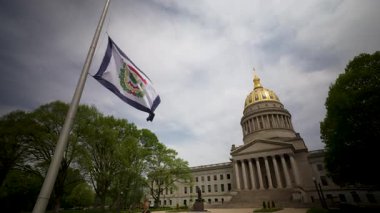Batı Virginia Eyalet Meclisi etkileyici kubbesini sergilerken eyalet bayrağı nazikçe dalgalanıyor. Çevreleyen ağaçlar Charleston 'daki tarihi mekana doğal güzellikler katıyor..