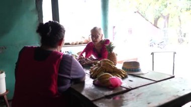 Ometepe, Nikaragua - 02 01 2025: Neşeli bir kadın, Nikaragua 'daki Ometepe Adası' nda taze meyvelerle çevrili Moyogalpa 'da yerel bir satıcıyla canlı bir sohbet ediyor..