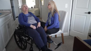 90 'lı yaşlarda yaşlı bir kadın tekerlekli sandalyede otururken, kızı onlara arkadaşlık ve bakım sağlıyor ve rahat evlerinde sıcak bir atmosfer yaratıyor..