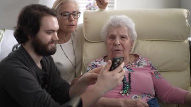Aydınlık bir bahar günü, bir kız ve torun evde birlikte vakit geçirirken akıllı telefondan yaşlı bir annenin fotoğraflarını gösterirler..