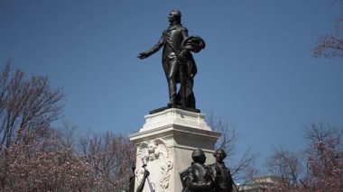 Marquis de Lafayette 'in heykeli Lafayette Meydanı' nda belirgin bir şekilde duruyor. Yakındaki ağaçlar çiçek açıyor ve Washington DC 'de gökyüzü açık mavi..