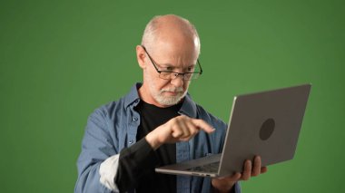 Gözlüklü son sınıf öğrencisi, bir dizüstü bilgisayar kullanmaya odaklanıyor. Duygu ve bağlılık duygusunu açık yeşil ekran bir arka plana yansıtıyor. Duyurular için ideal..