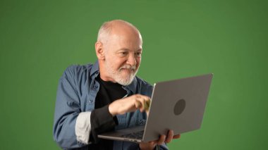 Üst düzey bir adam yeşil ekran arkaplanından izole edilmiş dizüstü bilgisayarını izlerken hayal kırıklığı gösteriyor. İş verilerini izliyor ya da performansı değerlendiriyor gibi görünüyor..