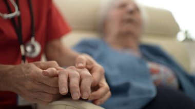 Bir bakıcı, hareket ve konfor aralığını geliştirmek için hastanın parmaklarına ve bileğine nazikçe masaj yapar. Bu kişisel bakım bir sağlık kliniğinde yapılır..