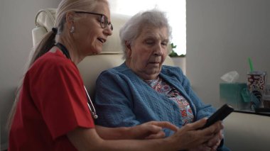 Bakıcı, sağlık merkezindeki yaşlı bir kadına destek sağlamaktadır. Anlamlı bir sohbete girişmişler, özen gösteriyorlar..