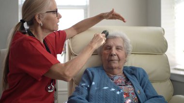 Bir bakıcı, sıcak ve rahatlatıcı bir ortamda yaşlı bir kadının saçını tarıyor, bir anlık ilgi ve rahatlığa odaklanıyor..