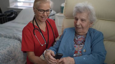 Bakıcı, yaşlı bir kadına sağlık merkezinde yardım eder, hafıza ve duygusal refahı geliştirmek için bağlanma ve etkileşimi teşvik eder..
