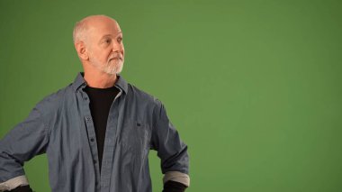 Düşünceli bir ifadeye sahip olgun bir adam yeşil ekrana karşı duruyor. Ürün duyurusu ya da promosyon aktivitesi için hazır..