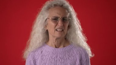 Kıvırcık beyaz saçlı ve gözlüklü orta yaşlı bir kadın elini kaldırıp 