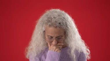 Çekici yüz hatları ve gözlüklü orta yaşlı bir kadın parmağını kaldırırken sevinçle gülümsüyor, canlı bir konuşma ya da fikir öneriyor..