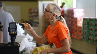 Yavaş çekimde, markette alışveriş yapan ve konuşan mutlu, olgun bir kadının yakın çekim görüntüsü..