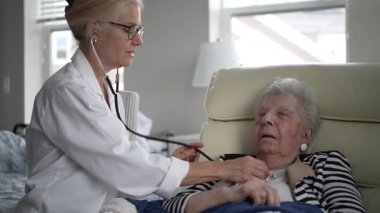 Bir sağlık uzmanı, evde yaşlı bir kadın için sağlık kontrolü yapar ve sağlık ihtiyaçlarının karşılandığından emin olur. Ortam sakin ve destekleyici, güveni arttırıyor..