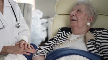 Olgun bir kadın evdeki bir sandalyeye rahatça oturur ve bir sağlık uzmanından sıcak bir ziyaret alır. Merhamet bu önemli etkileşim sırasında atmosferi doldurur.