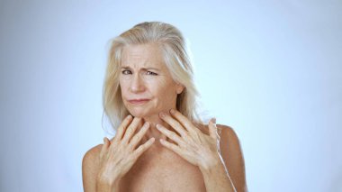 Olgun bir kadın spa seansı sırasında mutlu bir şekilde gülümser, rahatlatıcı, beyaz bir geçmişi olan, neşeli tavırlarını geliştirecek rahat bir yüz ifadesi sergiler..