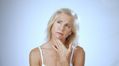 Olgun bir kadın, kaplıcada huzuru yansıtırken mutlu bir şekilde gülümsüyor. Yumuşak arka plan onun sakin tavrını geliştirir, rahatlamayı ve mutluluğu teşvik eder..