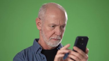 Olgun bir adam, mutlu bir yüz ifadesi sergilerken başparmağını kaldırır ve akıllı bir telefon tutar. Arkaplanda çok yönlülük için parlak yeşil bir ekran var.