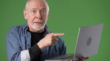 Orta yaşlı, sakallı bir adam yeşil ekran arka planına hevesle bakıyor. Etkileyici bir kişiliği ve enerjisi var..