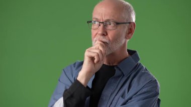 Gözlüklü olgun bir adam yeşil ekrana karşı düşünceli bir şekilde poz verir. İfadesi derin bir tefekküre işaret ediyor, portrelerin duygusal derinliğini arttırıyor..