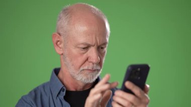 Orta yaşlı bir adam yeşil bir ekranın önünde duruyor, yüzünde şaşkınlık ifadesi var. Direkt olarak izleyiciye bakarken elleriyle hareket ediyor..