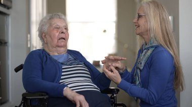 Sevgi dolu bir kız, yaşlı annesine tekerlekli sandalyede destek olur ve evinde rahat bir anı paylaşır. Aralarındaki bağ, günlük yaşamlarını ve bakımlarını ön plana çıkarıyor..