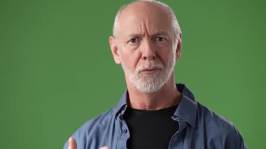 Beyaz saçlı ve sakallı orta yaşlı bir adam yeşil bir ekrana bakıp gülümsüyor. Bu portrede samimiyet ve yakınlık yayıyor..