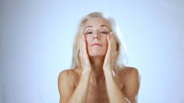 Olgun bir kadın, gençleştirici bir spa tedavisine girişip, cilt bakımını parlak ve sakin bir ortamda arttırarak neşe saçar..