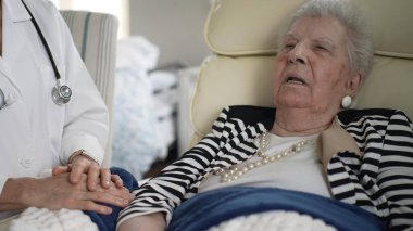 Olgun bir kadın evdeki bir sandalyeye rahatça oturur ve bir sağlık uzmanından sıcak bir ziyaret alır. Merhamet bu önemli etkileşim sırasında atmosferi doldurur.