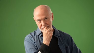 Sakallı son sınıf öğrencisi, canlı yeşil bir perdeye dayanan mutlu bir sırrı dinlerken sevinçten havalara uçar. Kıyafeti gündelik ama anlamlı..