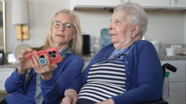 90 'lı yaşlarda bir kadın kızıyla görüntülü sohbet etmekten hoşlanır. Kapalı bir alanda birlikte otururken keyifli anılarını paylaşıyorlar, özenle çevrelenmiş..