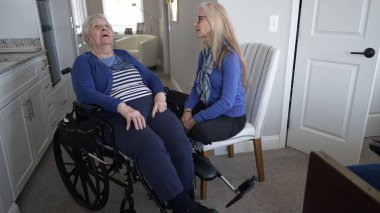 90 'lı yaşlarda yaşlı bir kadın tekerlekli sandalyede otururken, kızı onlara arkadaşlık ve bakım sağlıyor ve rahat evlerinde sıcak bir atmosfer yaratıyor..