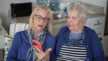 90 'lı yaşlarda bir kadın, anılarını ve sevgisini paylaşan, yakın ilişkilerini ve günlük yaşamdaki desteğini vurgulayan kızıyla görüntülü sohbet etmekten zevk alır..