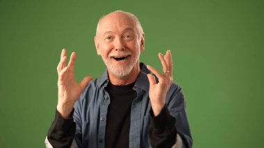 Olgun bir adam dua ederek ellerini bir arada tutar, düşünceli bir ifadeyle yukarıya bakar, sağlam yeşil bir zemine yaslanır..